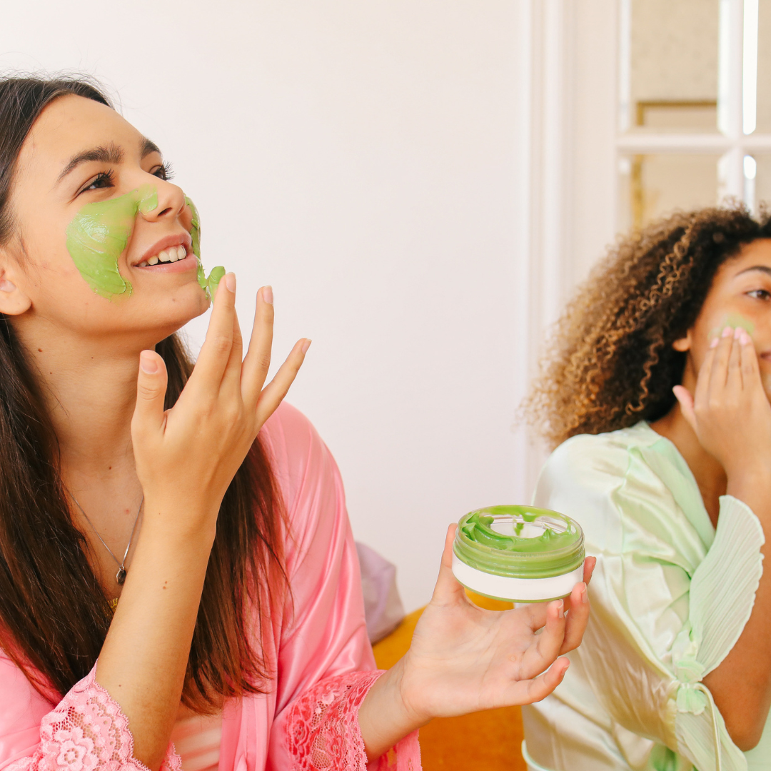 Women applying green face masks indoors.